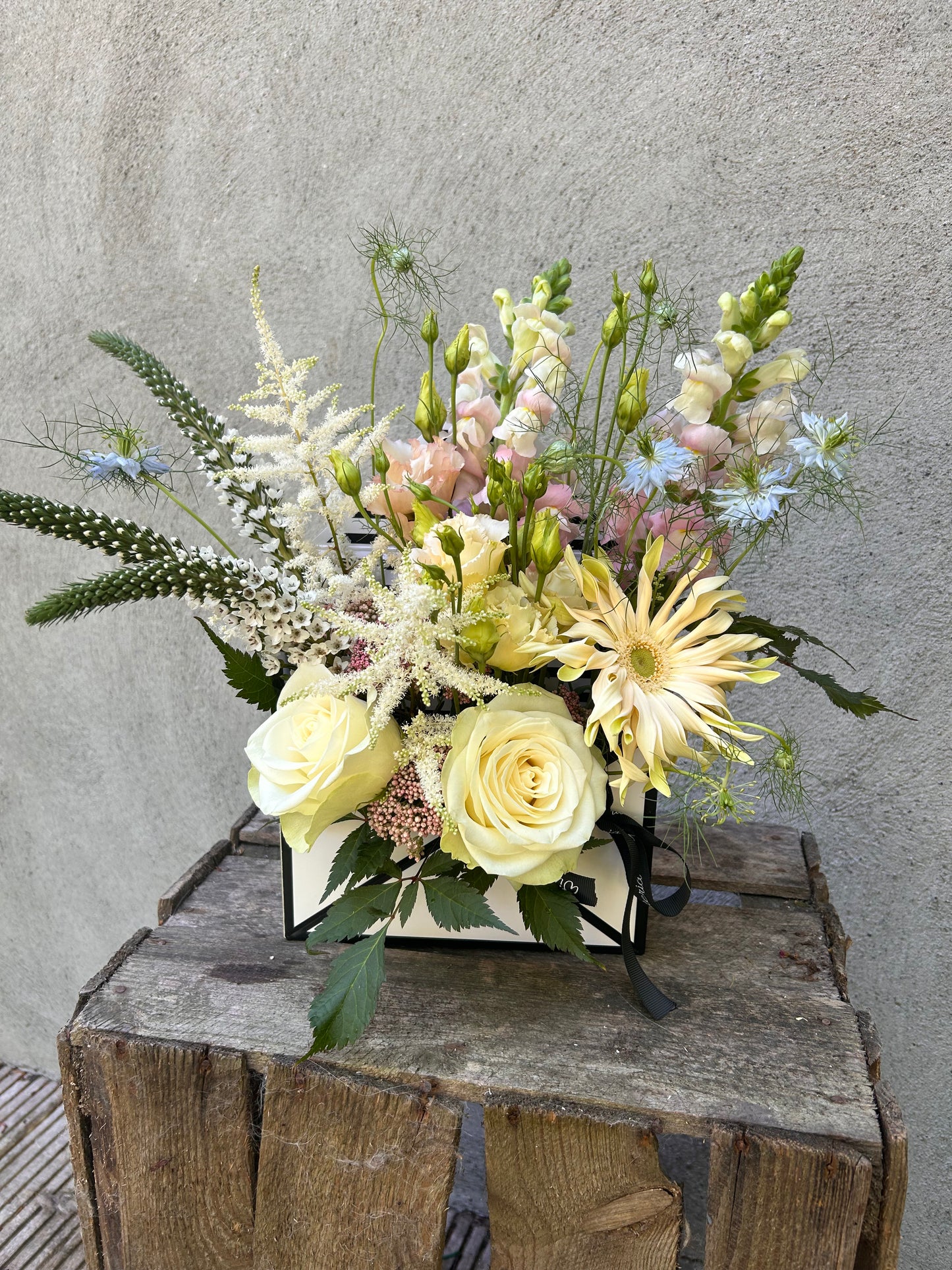 Floral arrangement in pastel tones, styled in an open envelope-shaped box