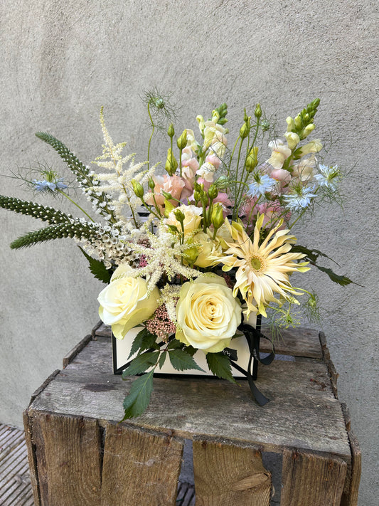 Floral arrangement in pastel tones, styled in an open envelope-shaped box