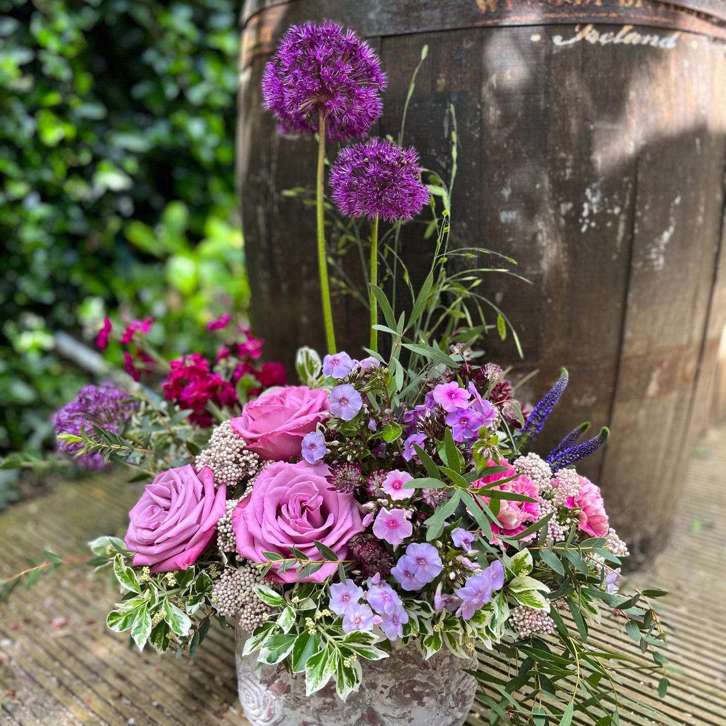 allium ands roses flower arrangement in a concret container